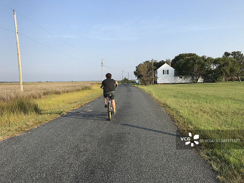 少年在东海岸的偏僻道路上骑自行车图片素材