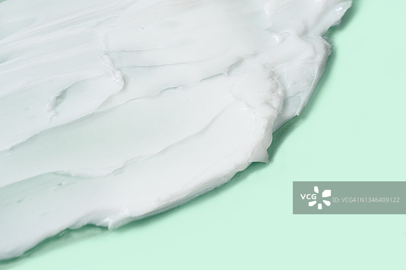 粉绿色背景上的白色保湿霜涂抹纹理图片素材