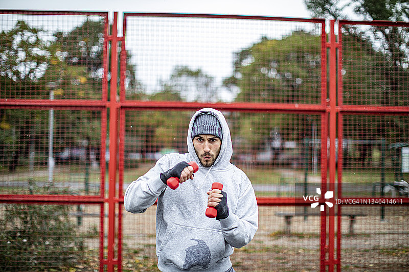 20多岁的年轻男子在雨天进行举重训练图片素材