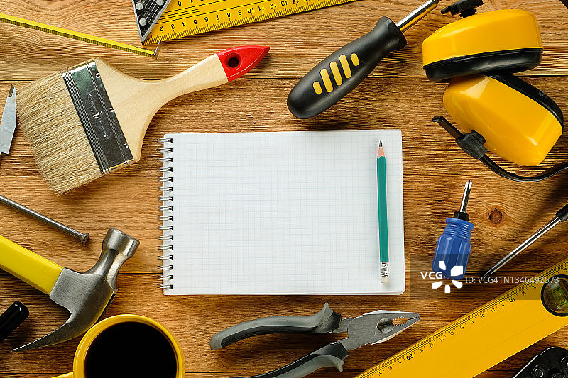 一杯茶或咖啡，专业建筑或家居维修的图纸和施工工具，在木桌上。工头或木匠工作场所的小吃或休息。建筑行业概念图片素材