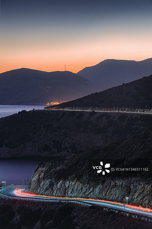 土耳其道路上汽车的尾灯弯曲环绕陡峭的海岸图片素材