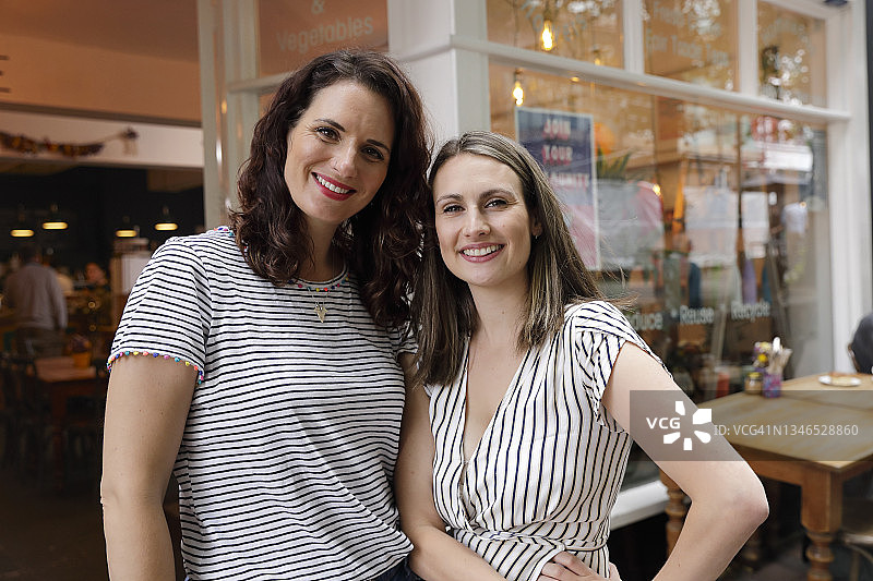 两位快乐的女性商业伙伴站在商店外图片素材