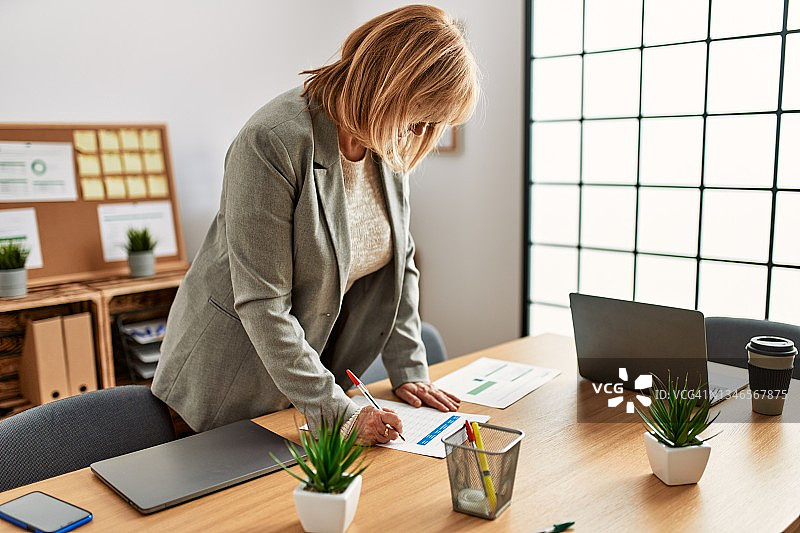 在办公室里工作，面带微笑的中年女商人图片素材