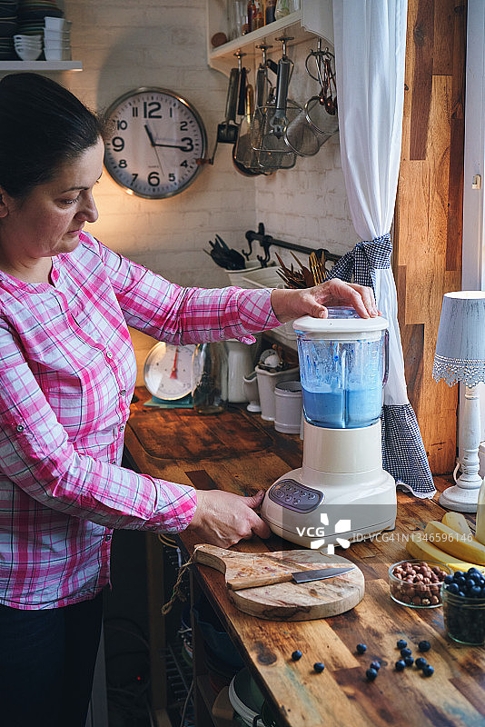 准备蓝莓螺旋藻思慕雪，碗中配有香蕉、浆果和超级食物图片素材