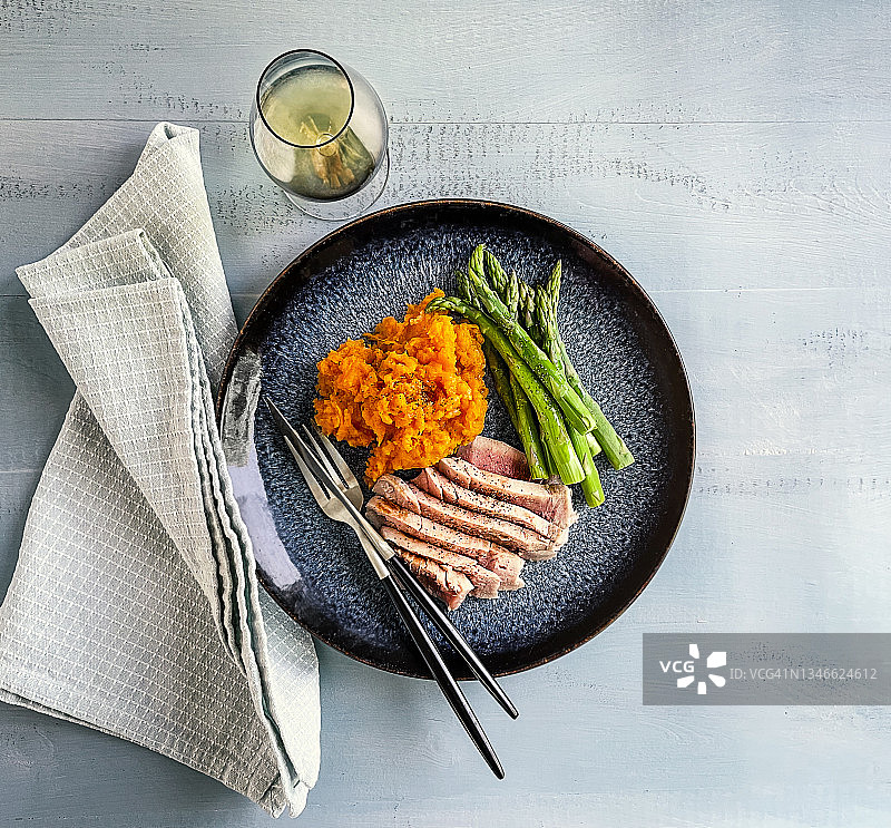 木质蓝色背景上的金枪鱼牛排芦笋甘薯泥图片素材