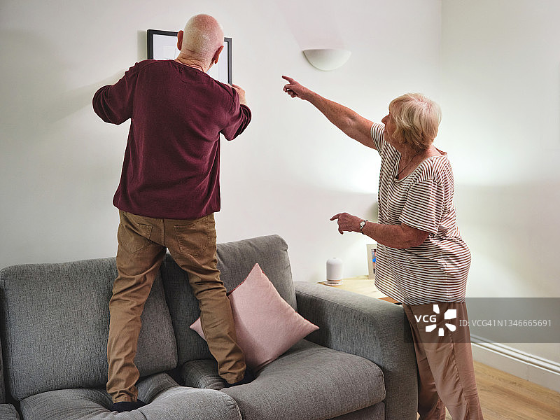 老年夫妇在家中墙上挂照片图片素材