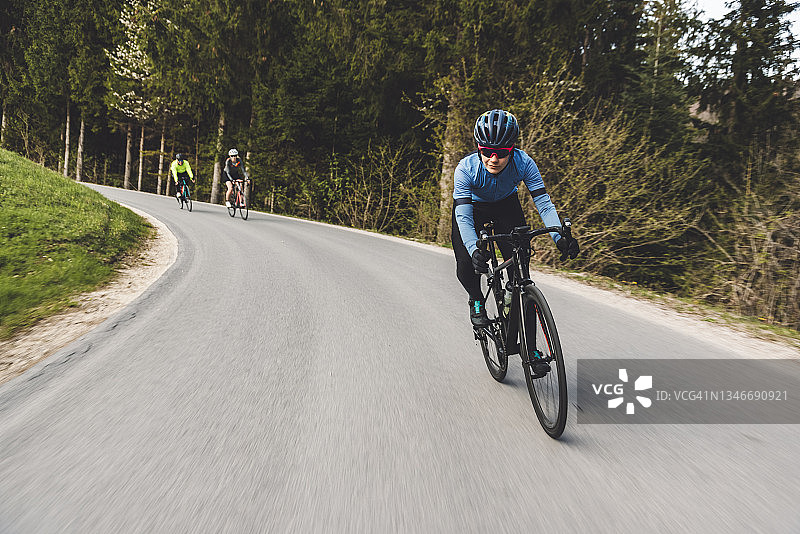 身穿蓝色衬衫的骑自行车者带领团队图片素材