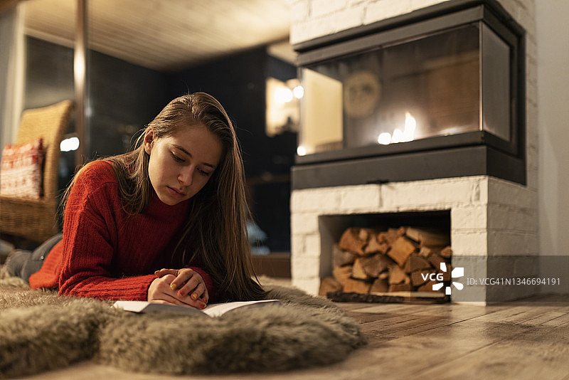 十几岁的女孩在壁炉旁看书图片素材