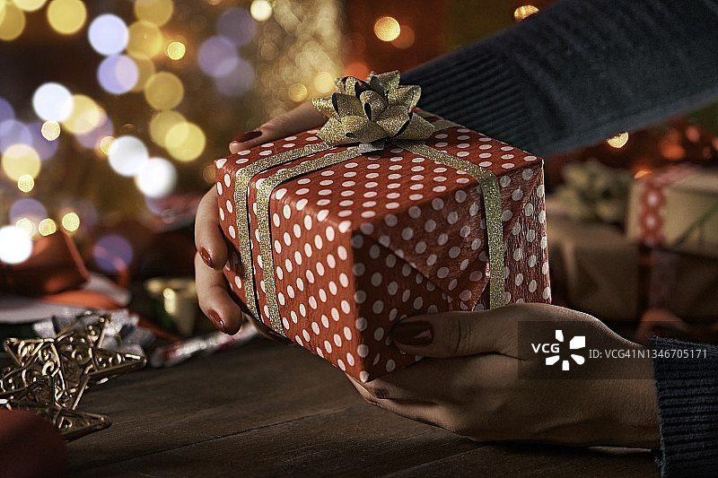 圣诞节主题：女人手拿包装好的圣诞礼物，留有复制空间图片素材
