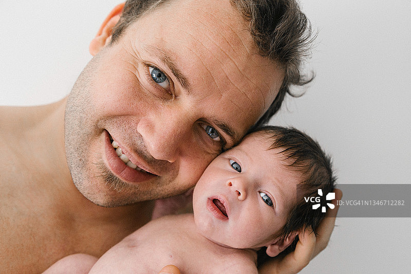父亲抱着儿子，对着镜头微笑图片素材
