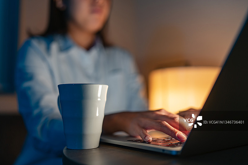 年轻女商人出差时在酒店房间用笔记本电脑工作到深夜图片素材