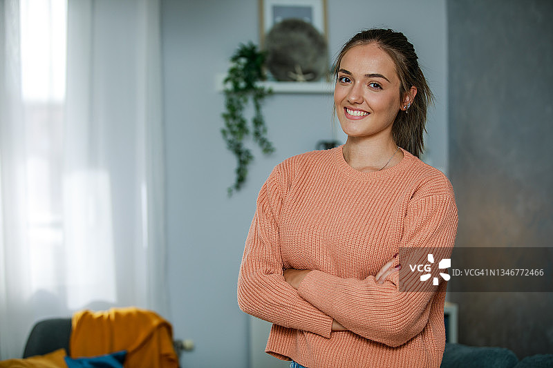 自信的年轻女人交叉双臂，对着镜头微笑图片素材