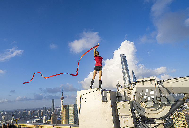 年轻芭蕾舞女演员在上海屋顶上用红丝带跳舞图片素材