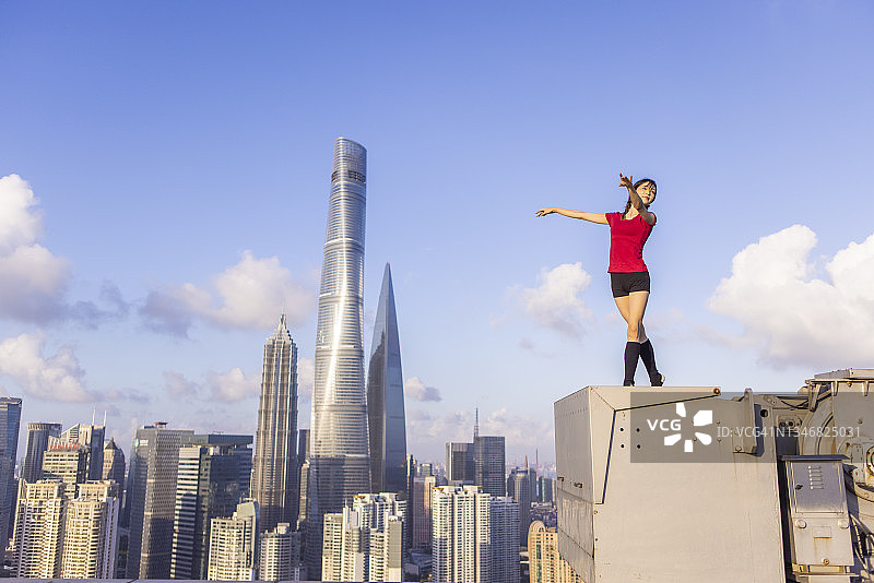 年轻芭蕾舞女演员在上海屋顶上用红丝带跳舞图片素材