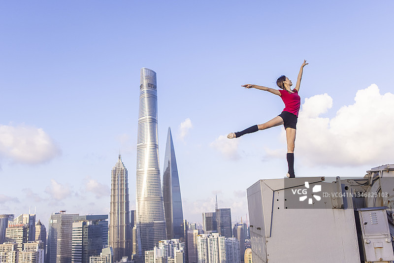 年轻芭蕾舞女演员在上海屋顶上用红丝带跳舞图片素材