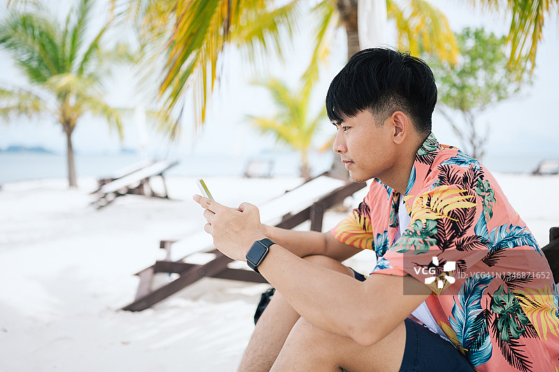 年轻的亚裔游客在白色沙滩上使用社交媒体图片素材