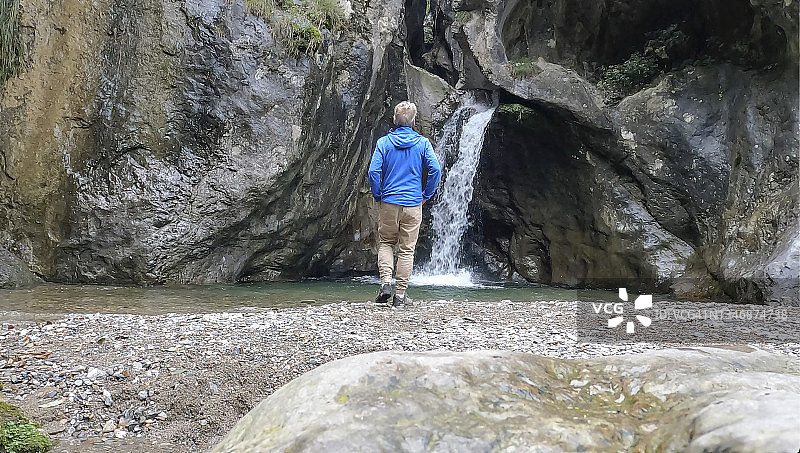 男人走向淡水池中的瀑布图片素材