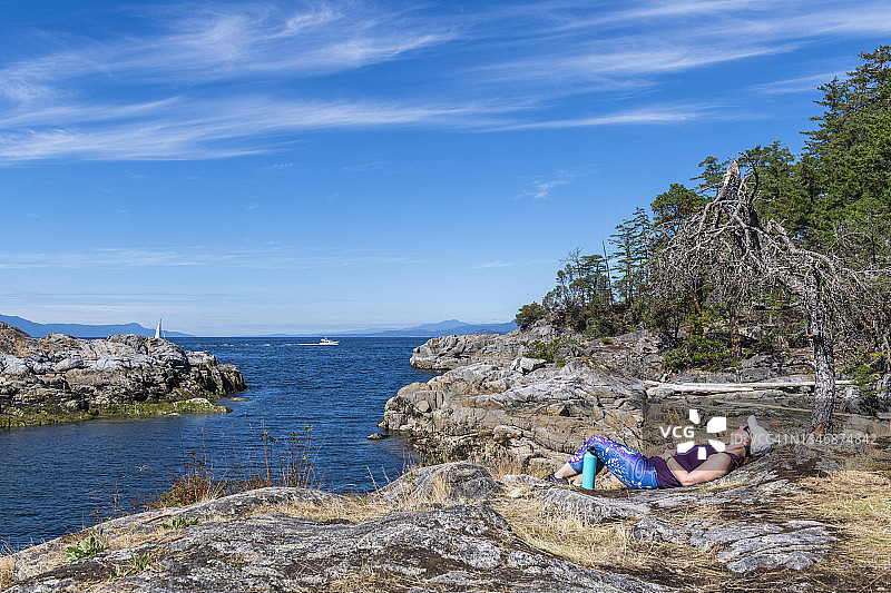女徒步者在清晨的海边悬崖上放松身心图片素材