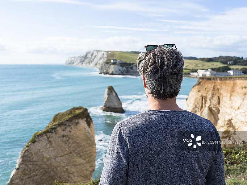 一个男人站在悬崖上看着淡水湾——库存照片图片素材
