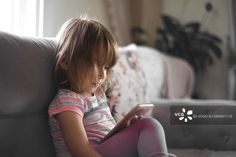 玩智能手机的可爱小女孩肖像图片素材