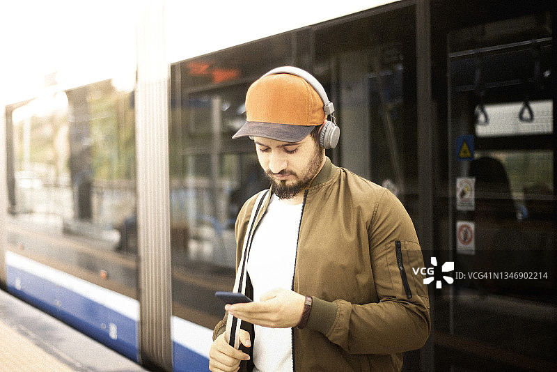 年轻男子在火车站使用手机图片素材