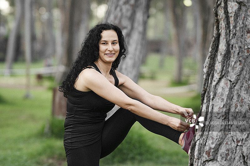 一位快乐的运动型女性系鞋带时看着镜头的肖像图片素材