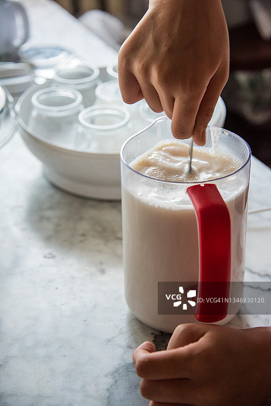 用勺子将酸奶混合到牛奶中，用玻璃罐酸奶机制作自制酸奶图片素材
