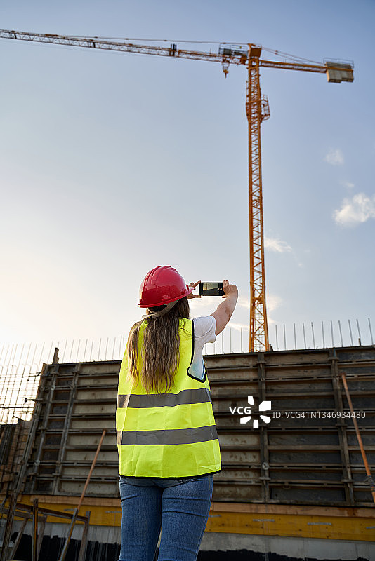 在建筑工地使用手机拍照的白人建筑师，行业和建筑概念图片素材