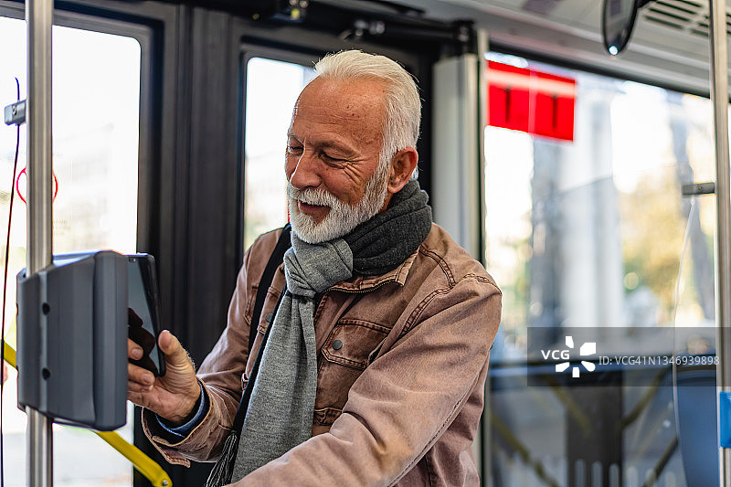 年长的男人用手机支付公交车票图片素材