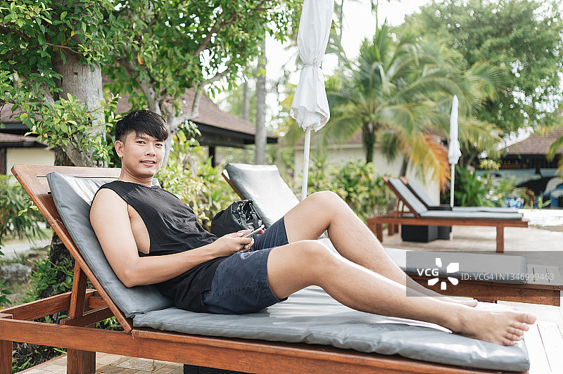 亚洲商务投资者在度假时使用手机投资，在海滩上查看股票和加密货币价格图片素材