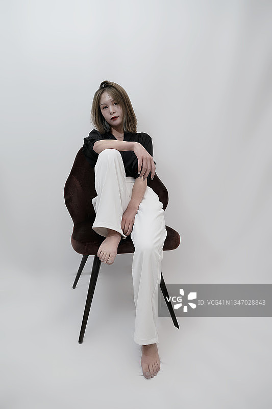 一位面向镜头坐在椅子上的时尚女性图片素材