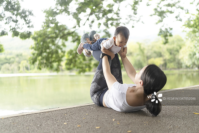 亚洲年轻女性穿着运动服在公园里和女儿玩耍图片素材