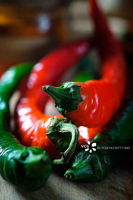 木制背景或厨房桌子上成熟和未成熟的红绿辣椒，有机农产品种植，美食烹饪香料图片素材