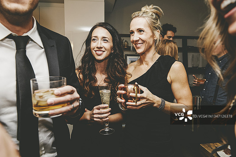 微笑的女性朋友在聚会中看着男人说话图片素材