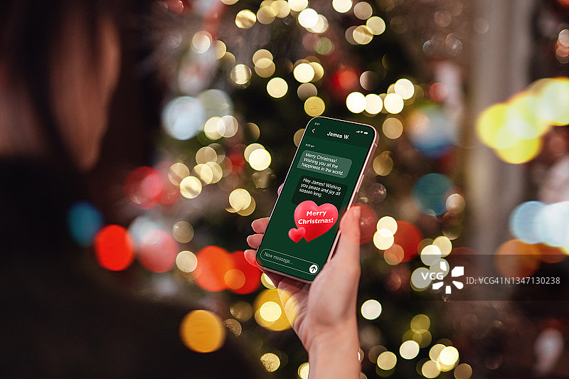 年轻女人使用智能手机发送圣诞祝福图片素材