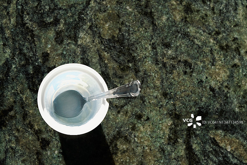 岩石表面上的空塑料杯和茶匙图片素材