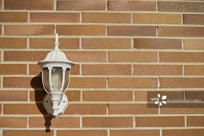 阳光明媚的露台上橙色砖墙上的墙灯图片素材