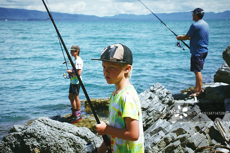 孩子和父亲在沿海岩石上钓鱼图片素材