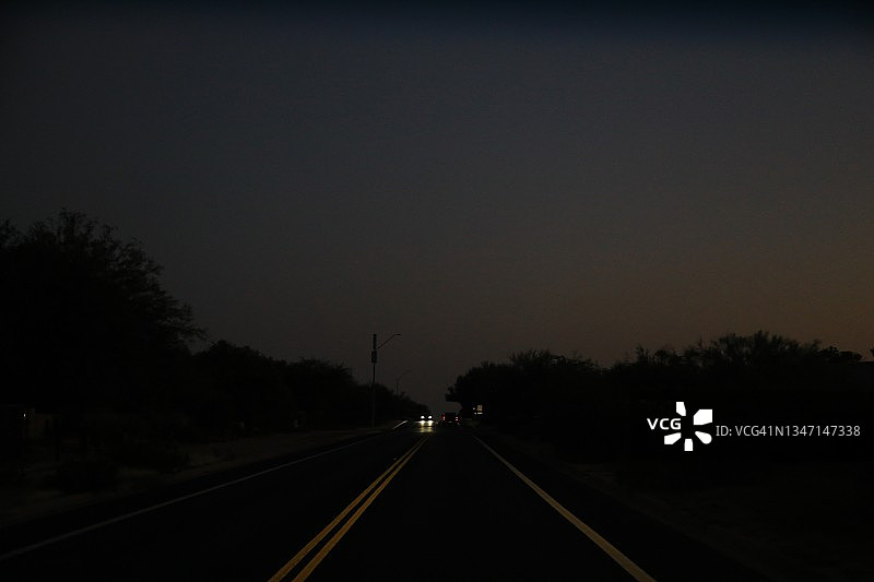 夜晚道路上行驶的车辆的照明前灯图片素材