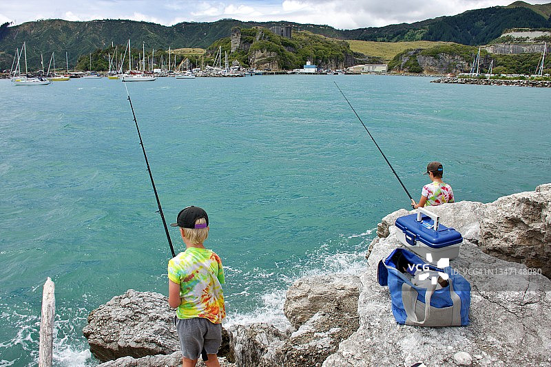 在海边岩石上钓鱼的孩子们图片素材