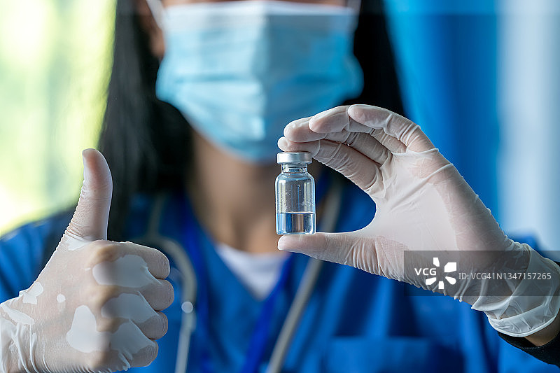 医生或科学家在实验室里拿着装有新冠疫苗的小瓶，准备进行流感疫苗注射。图片素材
