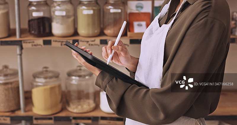 女店主使用平板电脑进行库存盘点图片素材