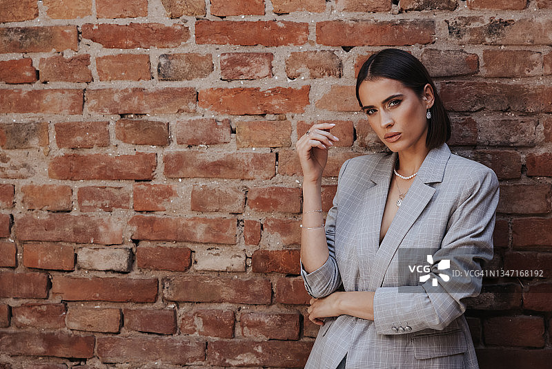 在砖墙前摆姿势的年轻女子图片素材