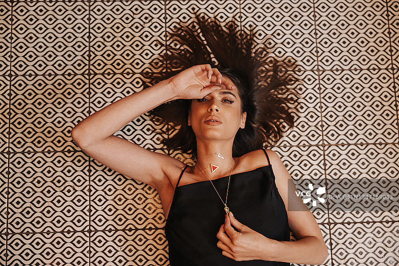 躺在瓷砖地板上的漂亮黑发女人图片素材