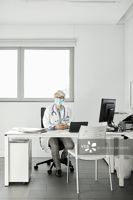 疫情期间医生坐在诊所的办公桌前图片素材
