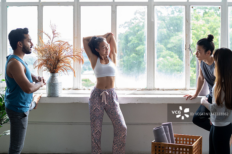 年轻的亚洲瑜伽女教练与学生一起伸展运动图片素材