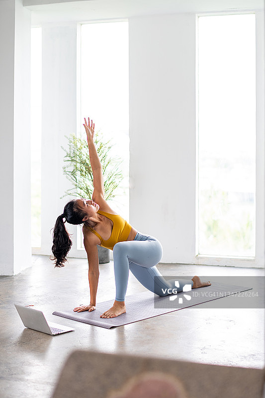 亚洲女子使用笔记本电脑练习瑜伽图片素材