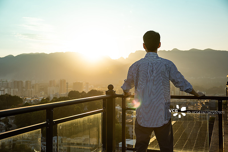 年轻商人于屋顶眺望日落图片素材