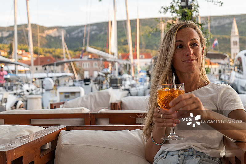女人在日落时分的酒吧里喝着Spritz放松身心图片素材