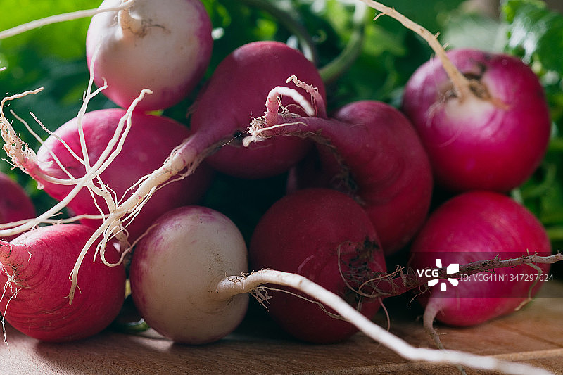 砧板上带叶的鲜亮红萝卜，厨房或餐桌背景。家庭种植有机蔬菜水果。收获，烹饪。素食、纯素和生食饮食。图片素材